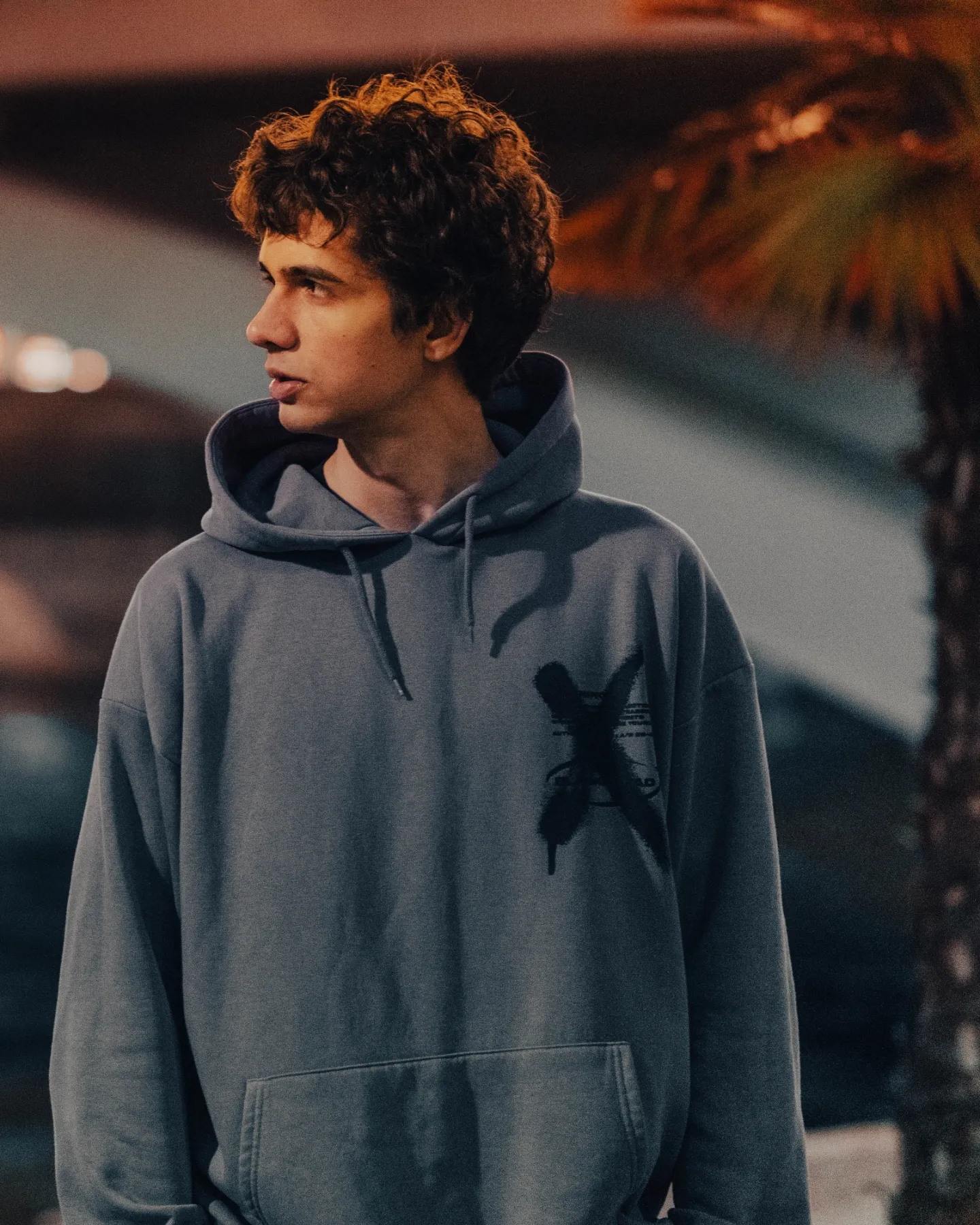David Black wearing a gray hoodie outdoors at night, looking to the side